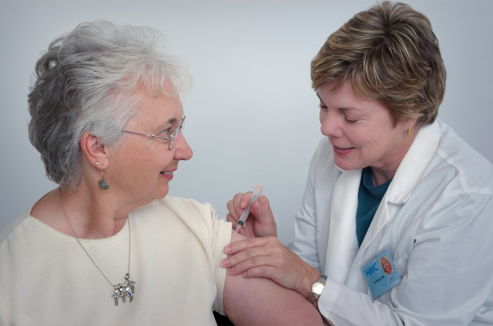 A smiling senior patient receiving a vaccination